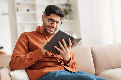 Man sitting on couch reviews financial records to help calculate his debt-to-income ratio (DTI).