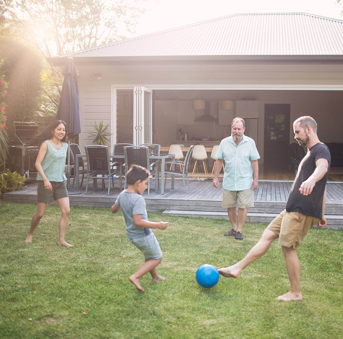 Family kicking a soccer ball in their backyard