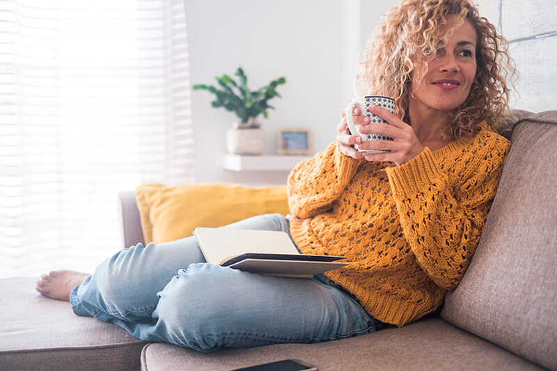 A first time homebuyer drinking coffee on her couch