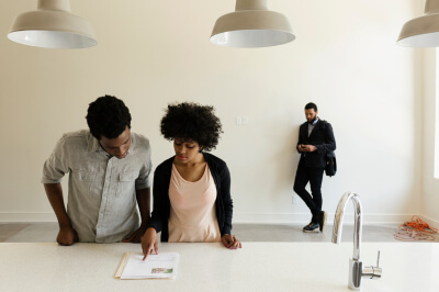 Couple reviews their mortgage pre-approval in their house with a realtor.