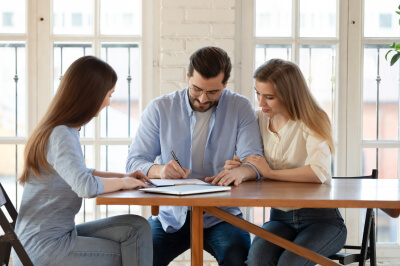 Couple signing closing cost paperwork with a loan officer.