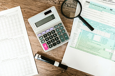 Calculator on a table with papers and a pen