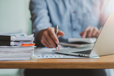 Man sitting at desk calculates monthly private mortgage insurance (PMI) while surrounded by paperwork.