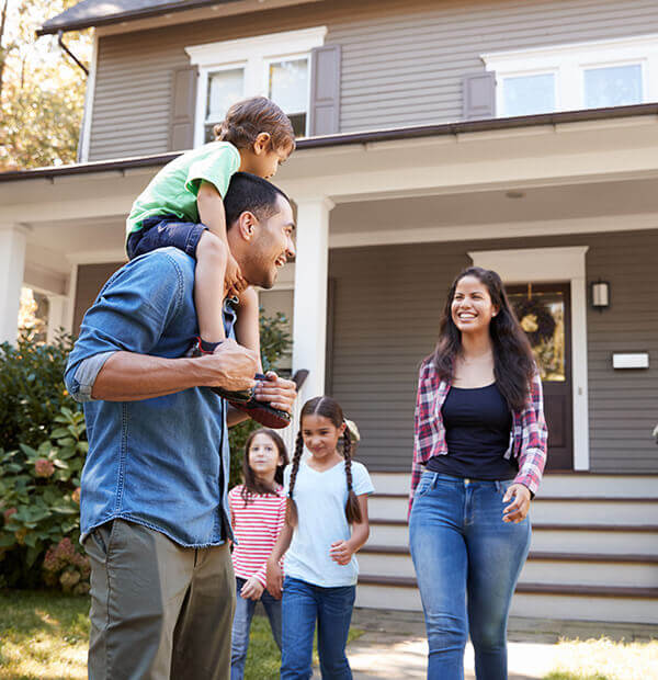 A family together walking out the front door of their new home.