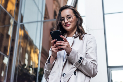 Woman on the street in New York City contacts her NYC mortgage lender using her cell phone.