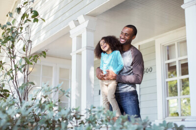 Father and daughter stand outside of their new home